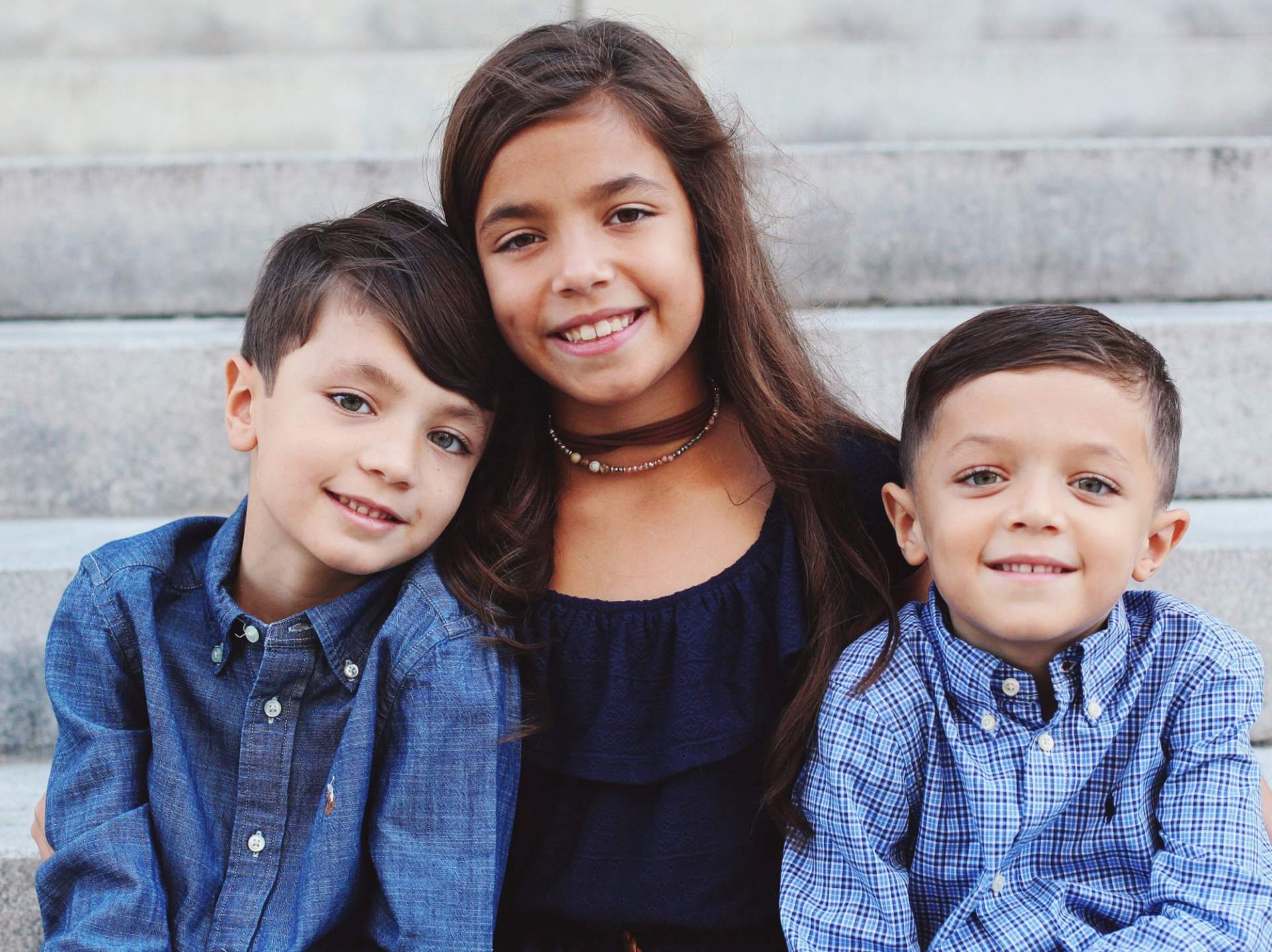 Two boys with a young lady in-between them, all smiling